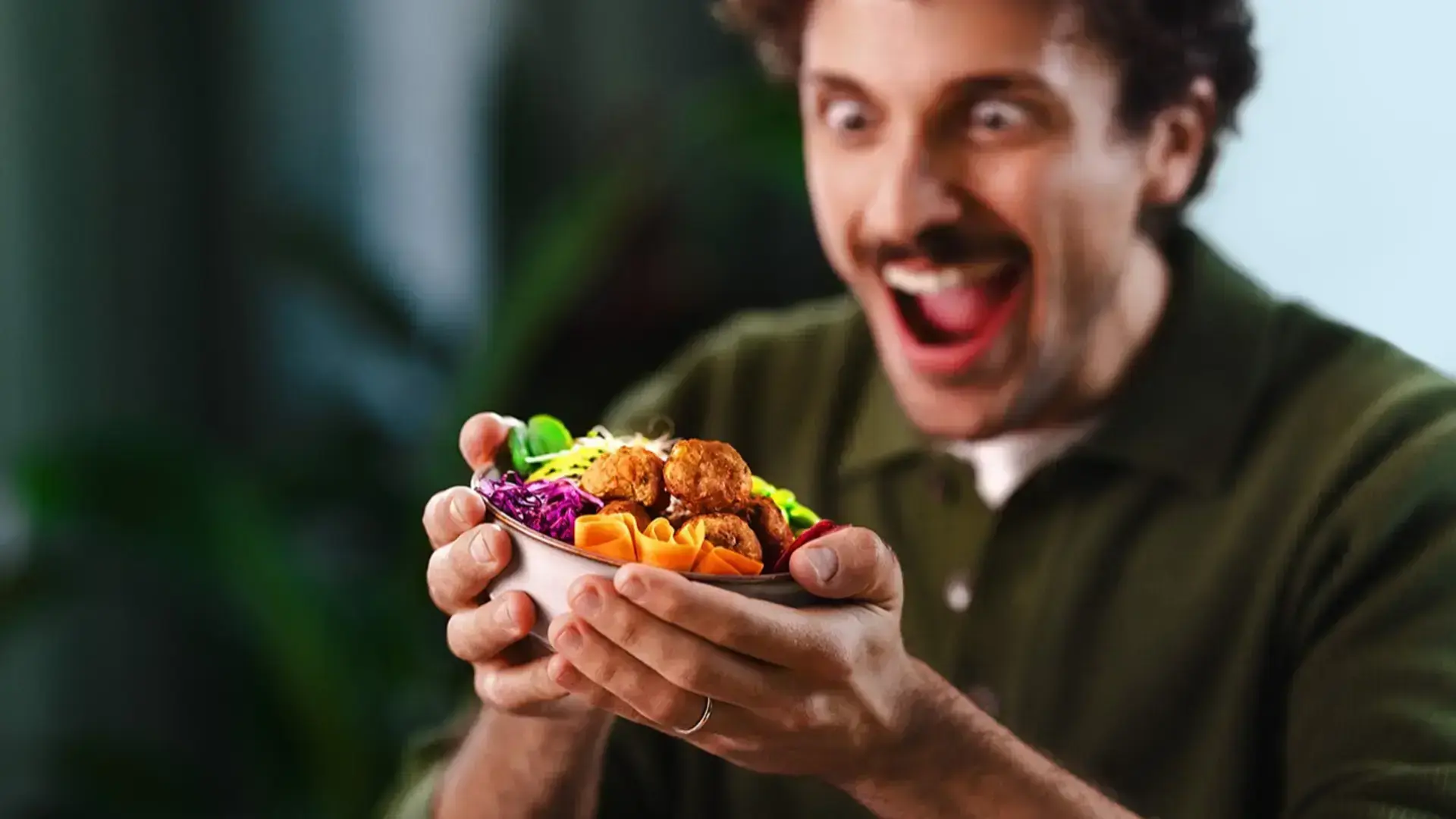 A man looking happily at the food he is holding on his hands.