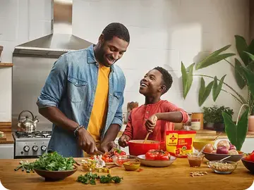 Un père et son fils cuisinent dans la cuisine en riant ensemble.